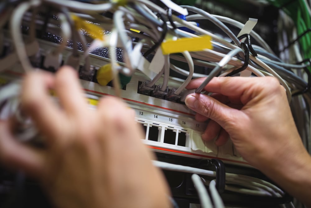 Technician Plugging Patch Cable in Rack Mounted Server